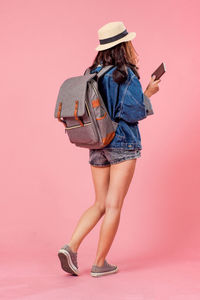 Rear view of woman standing against pink background