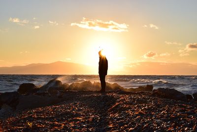 Silhouette woman standing at beach during sunset