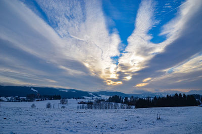 Scenic view of snow covered landscape against sky during sunset