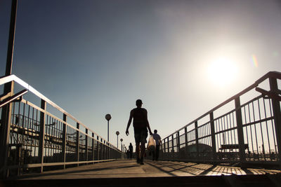 Man on bridge against sky during sunset