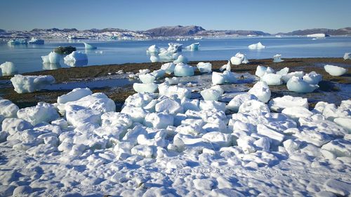 Snow on sea shore against blue sky