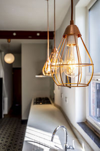 Close-up of illuminated light bulb hanging at home