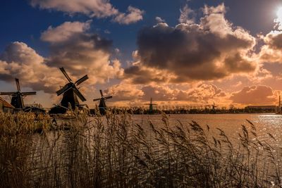 Panoramic view of traditional windmill on field against sky at sunset