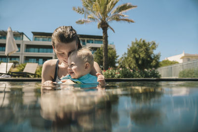 Happy mother and baby son in swimming pool