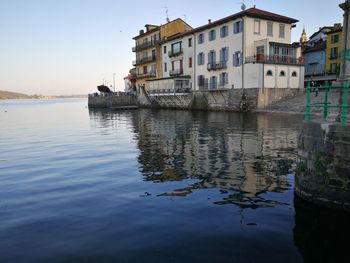 Buildings by lake in city against sky