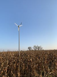 Wind turbines on field against clear sky