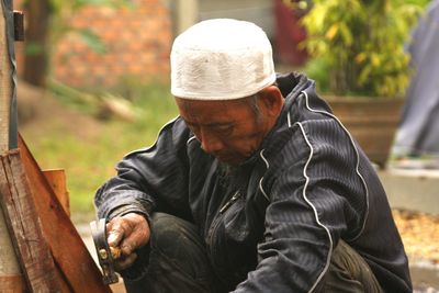 Portrait of man wearing hat sitting outdoors