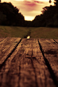 Surface level of wooden railing at sunset