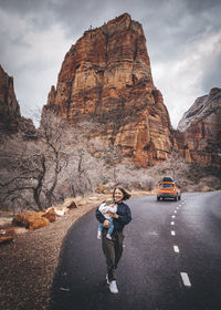 People on road by rock formation against sky