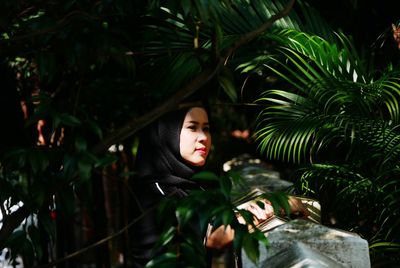 Portrait of young woman against tree