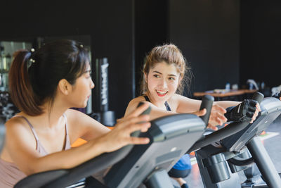 Smiling women talking while exercising in gym