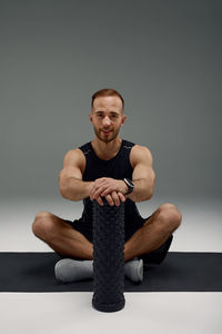 Portrait of young man exercising against black background