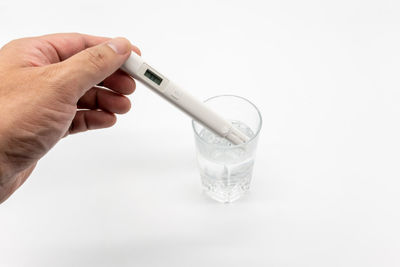 Midsection of person holding glass over white background