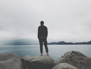 Rear view of man looking at sea against sky