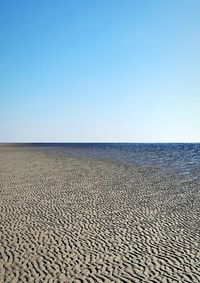 Scenic view of beach against clear blue sky