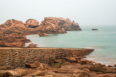 Scenic view of rocks in sea against clear sky