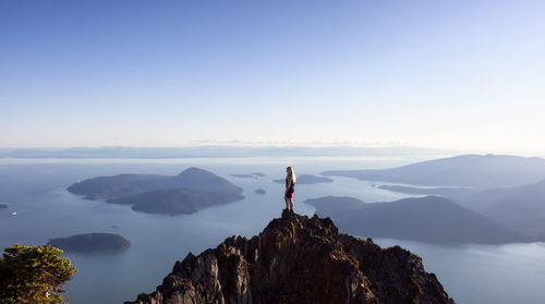 Man standing on rock against sky