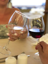 Midsection of woman toasting wineglass