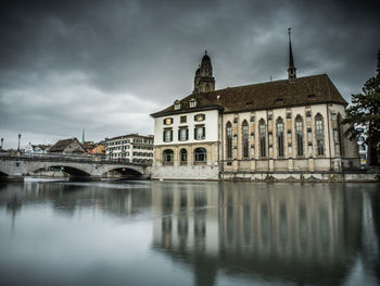 Arch bridge over river against buildings