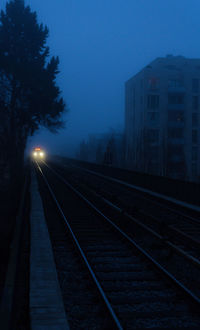 Railroad tracks against clear sky at night