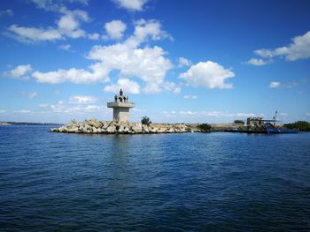 Lighthouse by sea against sky