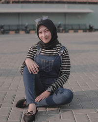 Portrait of teenage girl sitting on footpath