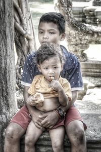 Brother sitting with sister outdoors