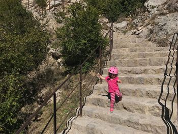 Full length of girl moving down on steps by plants