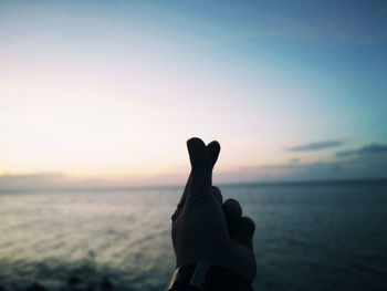 Midsection of silhouette man against sea during sunset