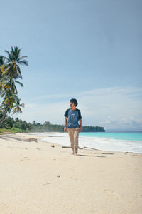 Rear view of man standing on beach against sky