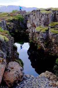 Man standing by rocks on cliff against sky