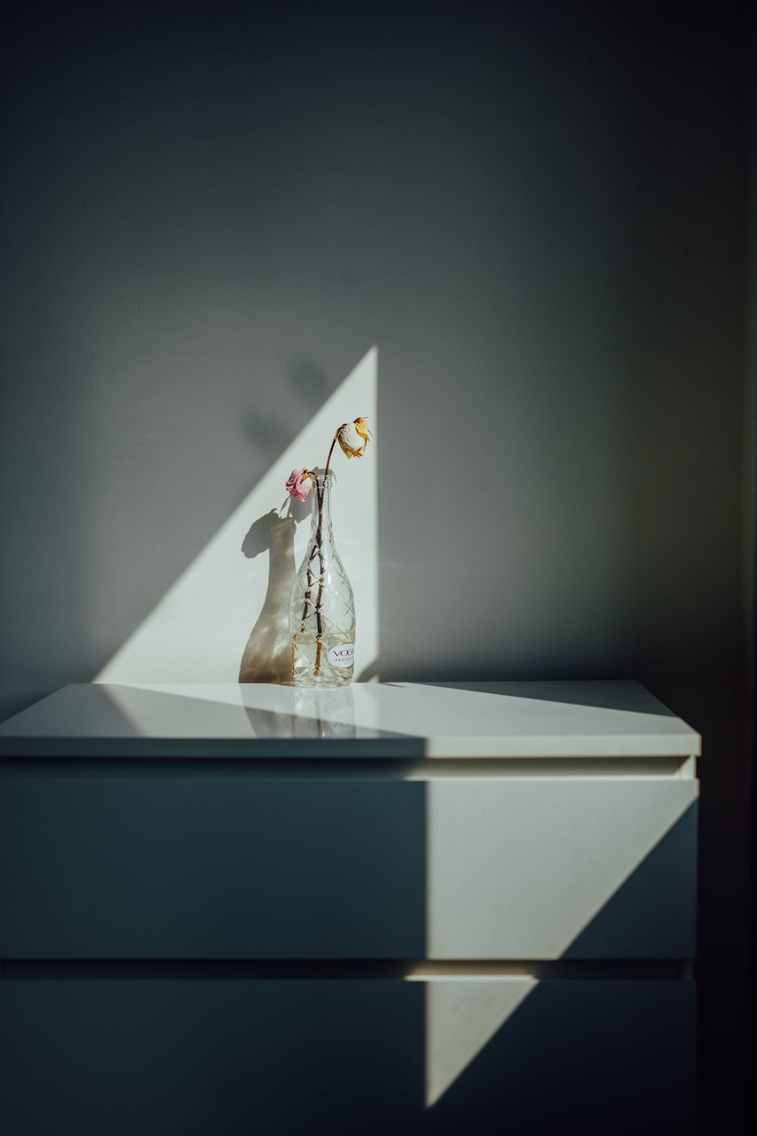 CLOSE-UP OF PAPER FIGURINE ON TABLE AGAINST WALL