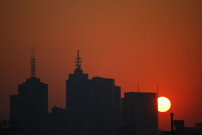 Silhouette of city against orange sky