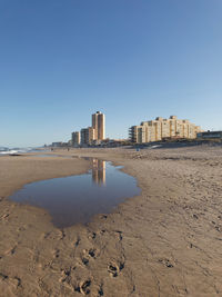 Buildings by sea against clear sky