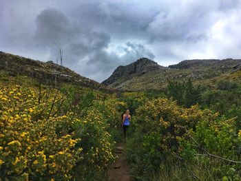 Rear view of woman walking on landscape against sky