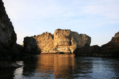 Rock formations by sea against sky