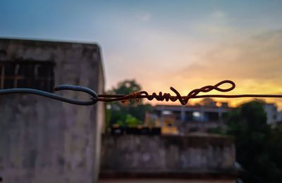 Close-up of metal cable against sky during sunset