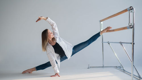 Full length of woman stretching against white backgrounds