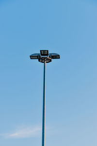 Low angle view of security camera against clear blue sky
