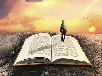 Man standing on book against sunset sky