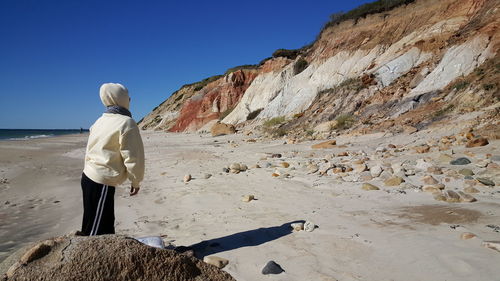 Woman standing at beach against clear sky