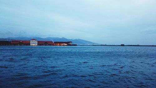 Calm blue sea with built structures against the sky