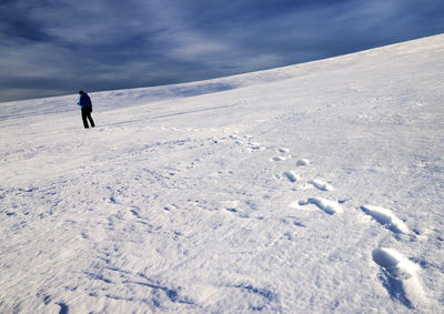 Rear view of hiker standing on snow covered mountain against sky