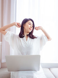 Young asian woman stretching her arms after using laptop.