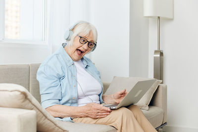 Young woman using laptop while sitting on sofa at home