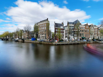 Buildings by river against sky
