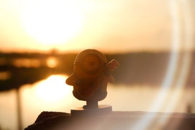 Close-up of statue on sea against sky during sunset