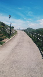 Road leading towards mountain against sky