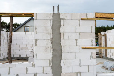 The walls of a house built of white brick with reinforced concrete pillars at the end of which