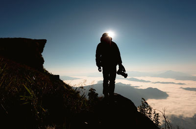 Rear view of silhouette man looking at mountains against sky
